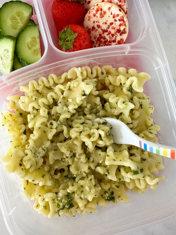 Close up of the nut free pesto pasta, being eaten with a plastic fork with a rainbow design.