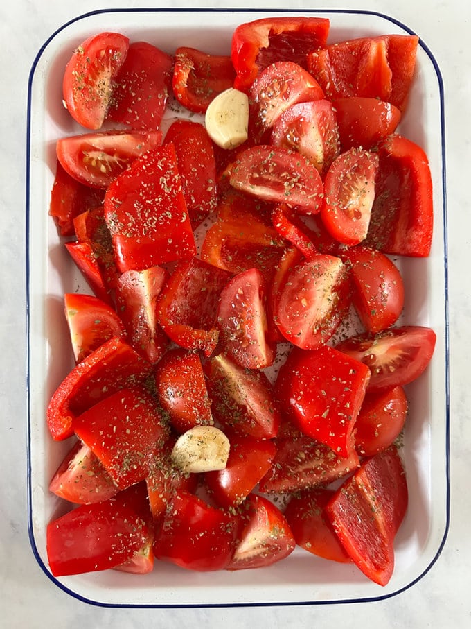 Chopped red peppers ans tomatoes in a oven prove dish ready to be roasted. 