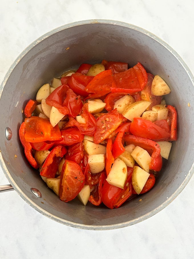 Oven roasted veggies and chopped potatoes are now added to a saucepan.