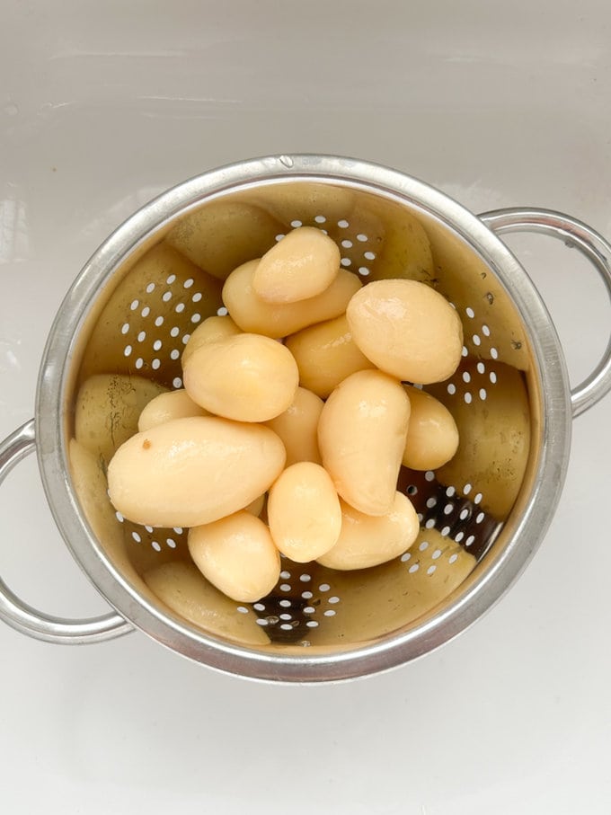 Tinned potatoes being drained on a colander.