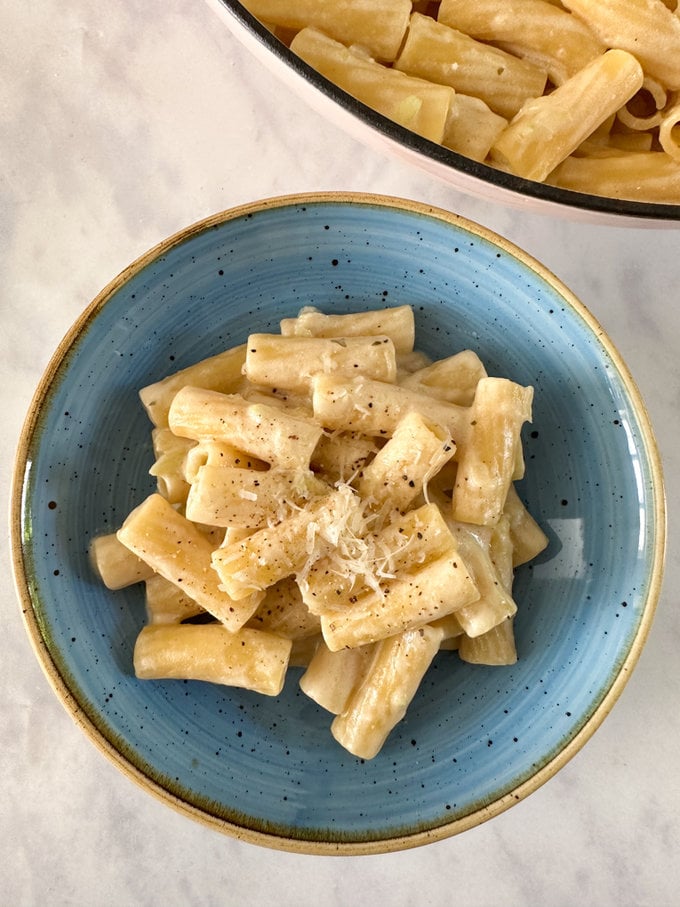 Broccoli stalk pasta served in a round blue bowl and garnished with grate cheese.