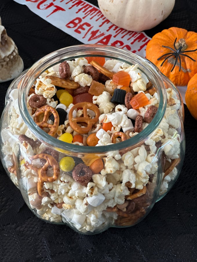 Halloween trail mix in a clear glass pumpkin shaped bowl.