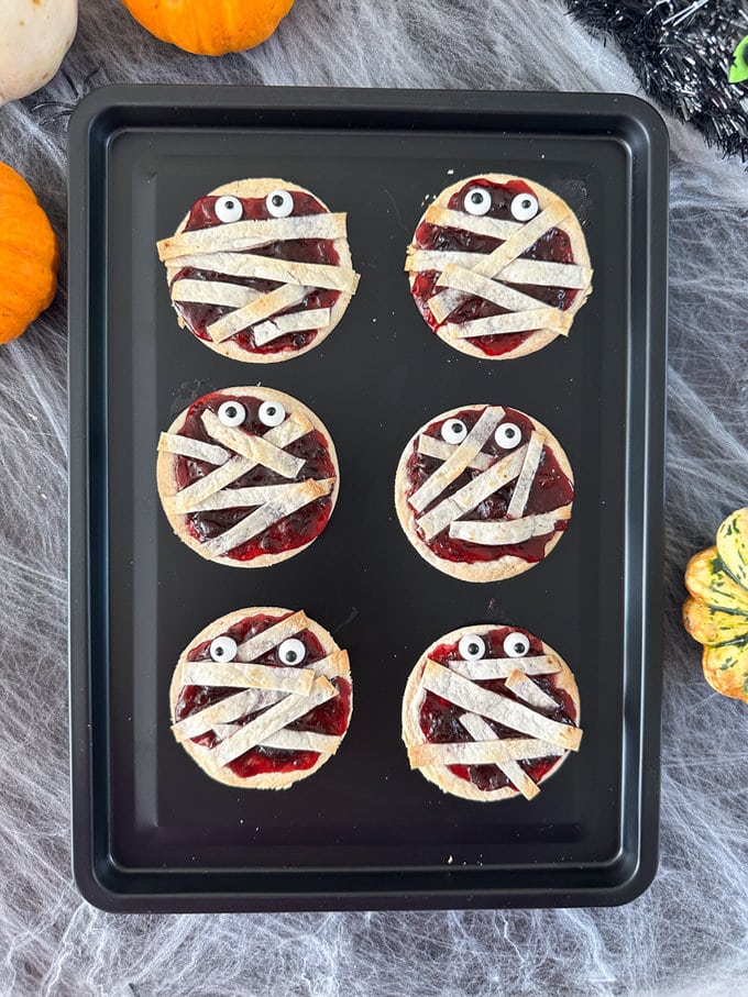 six jam mummy wrap tarts laying on a over tray.