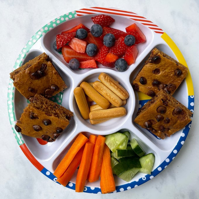 the Midi Pick Plate filled with chocolate chip cake bars, fresh fruit and veggies and mini breadsticks.