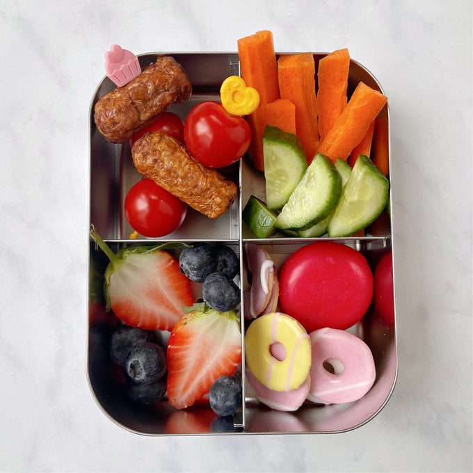 Mini Sausages and cherry Tomatoes on pick sticks from pick plates as part of a children's lunchbox.