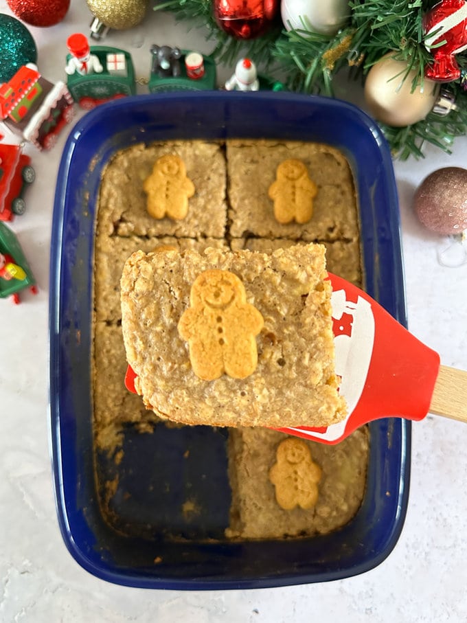 Gingerbread oats cakes served in a dark blue oven dish, topped with small gingerbread men for decoration.