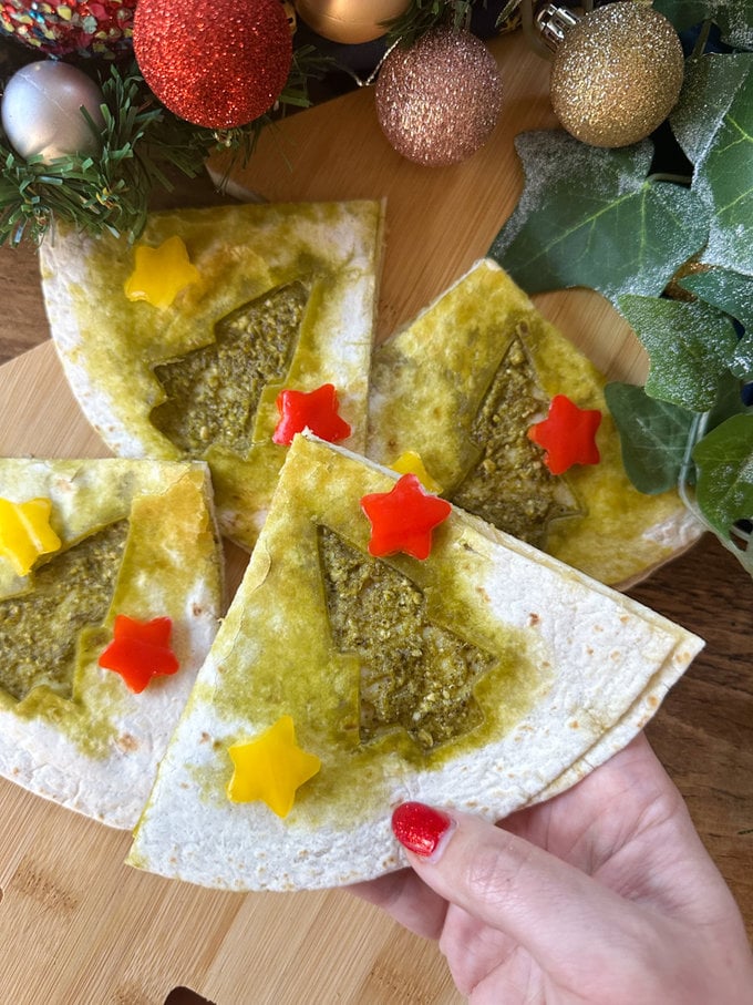 Christmas quesadillas arranged on a wooden chopping board surrounded by festive decoration. 