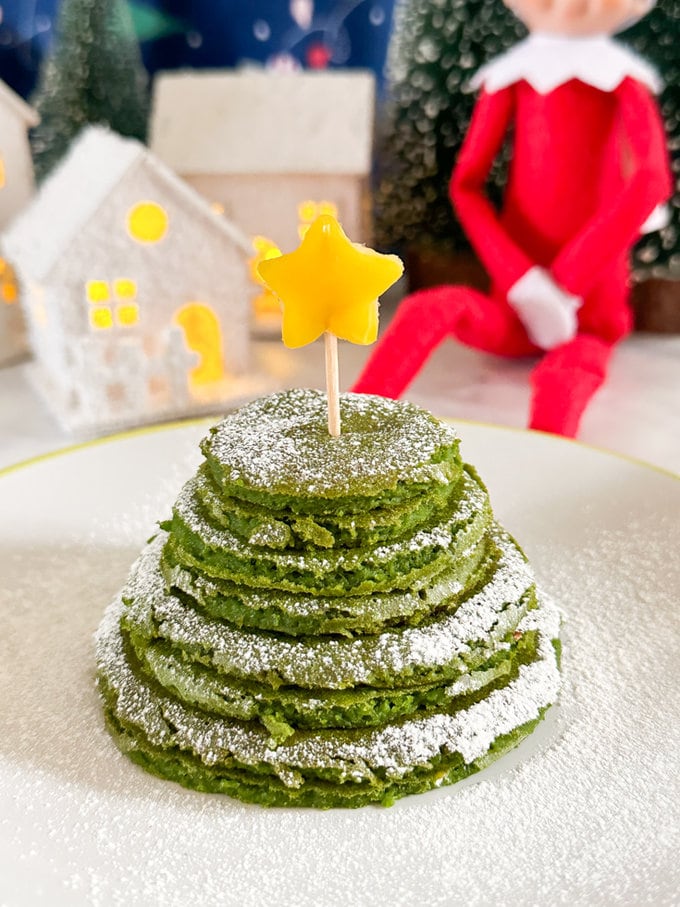 Close up of the elf Christmas tree green pancakes pile dusted in icing sugar.