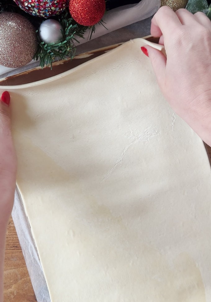 The other sheet of puff pastry being laid over the first sheet, with the layer of Nutella inbetween.