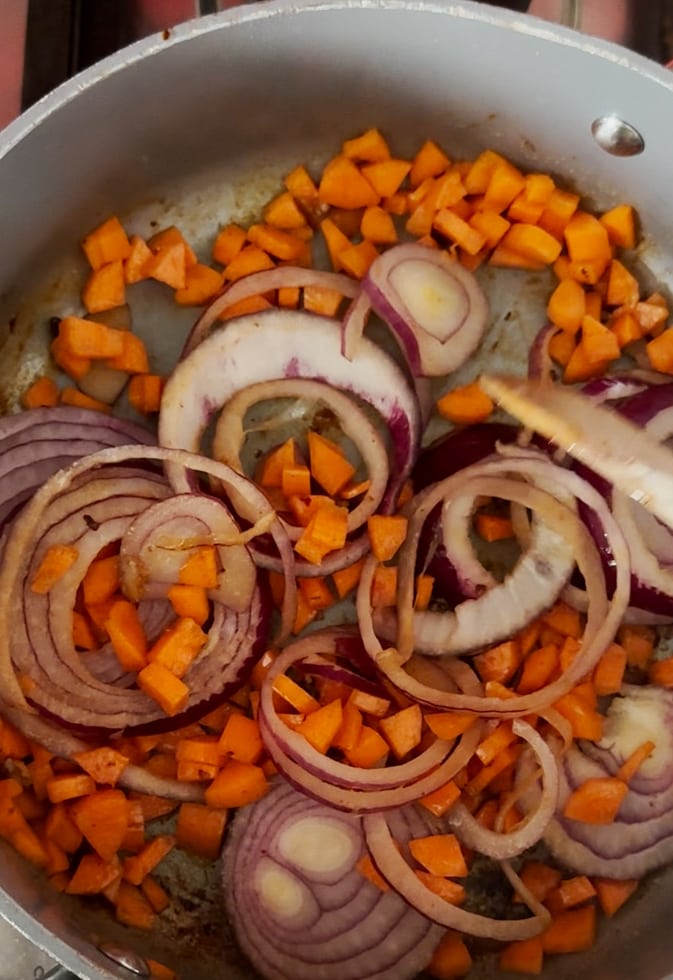 Carrots and onions added to frying pan.