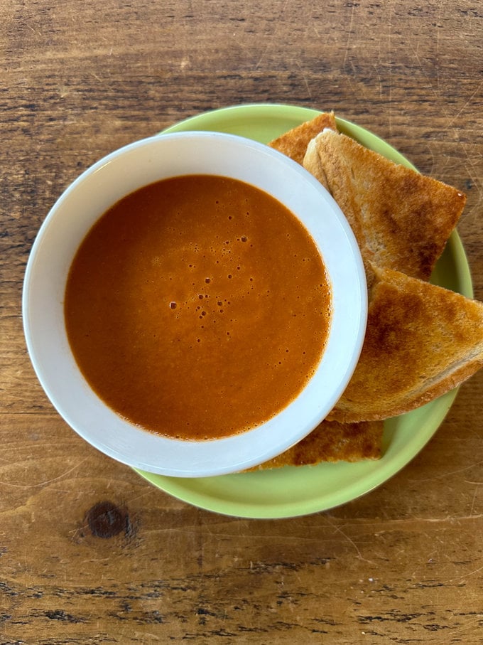 Airfryer tomato soup served in a white soup bowl,served with a slice of buttered white bread.
