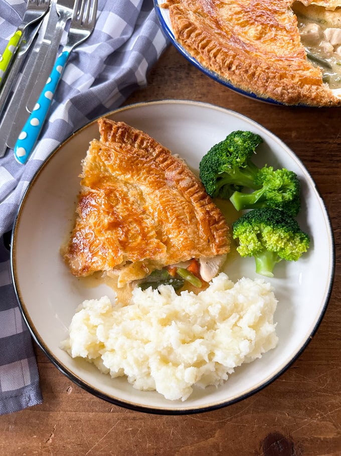 Easy chicken pie served on a round,white dinner plate. served with fresh mashed potato and broccoli.