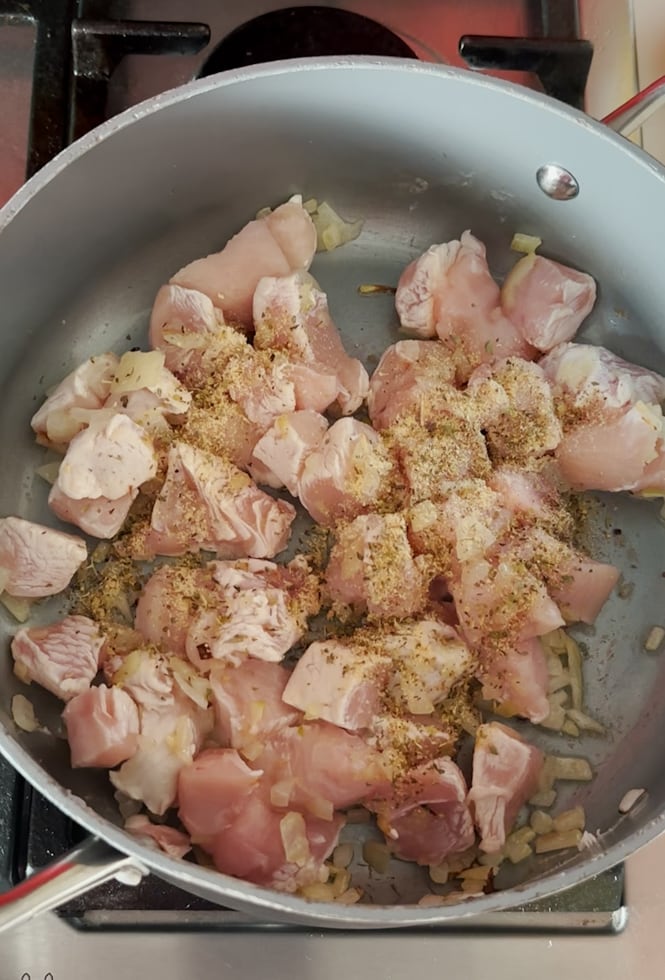 Chopped chicken frying in a pan.