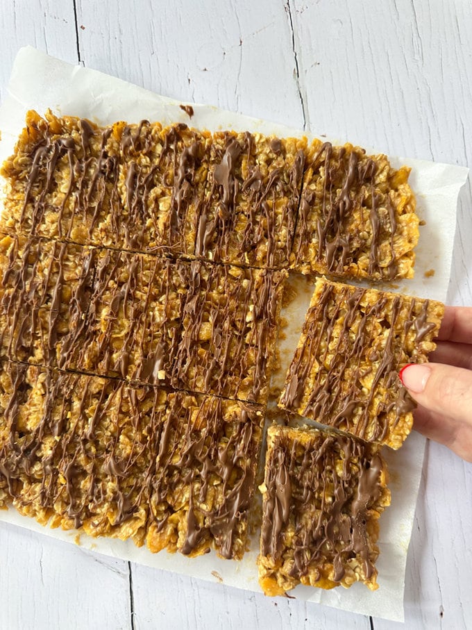 No bake cornflake bar slab laying on a piece of grease proof paper and divided into bite size pieces.