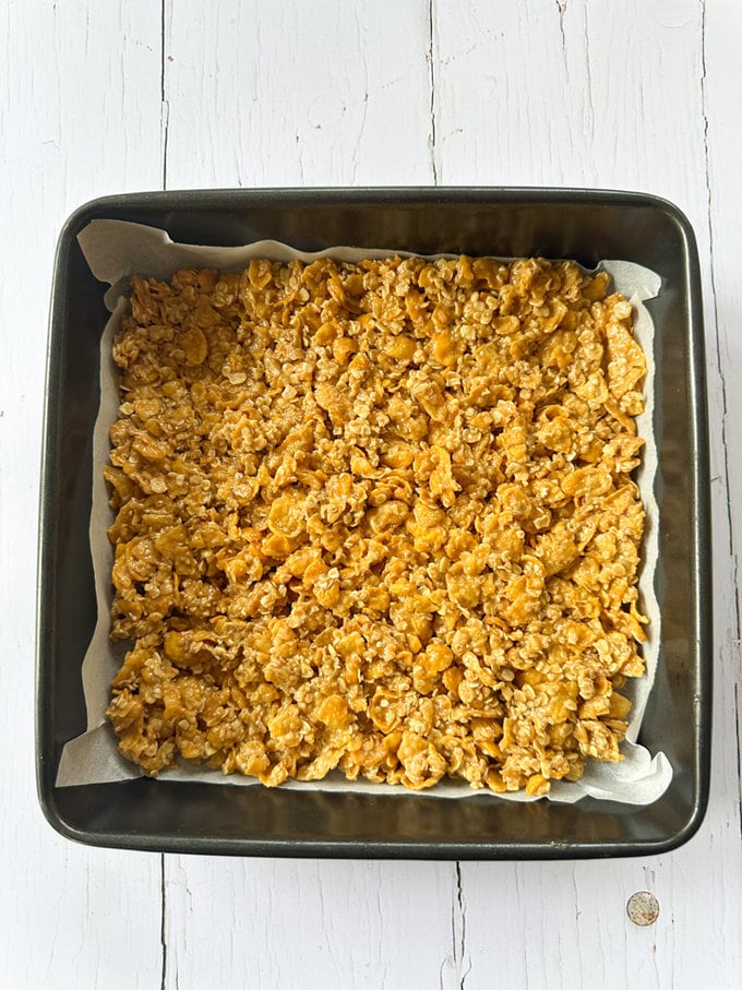 Cornflake mixture added to a large lined dish.