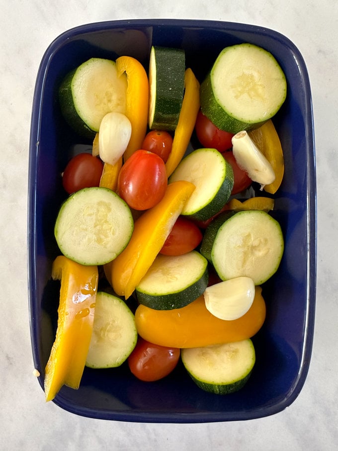 Bright veggies chopped and arranged in  a blue oven dish.