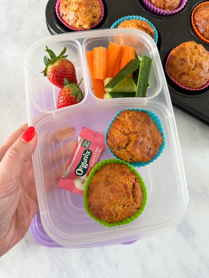 Leftover Bolognese Muffins in a divided children's lunchbox and accompanied by sliced carrots and cucumber with two whole fresh strawberries. 