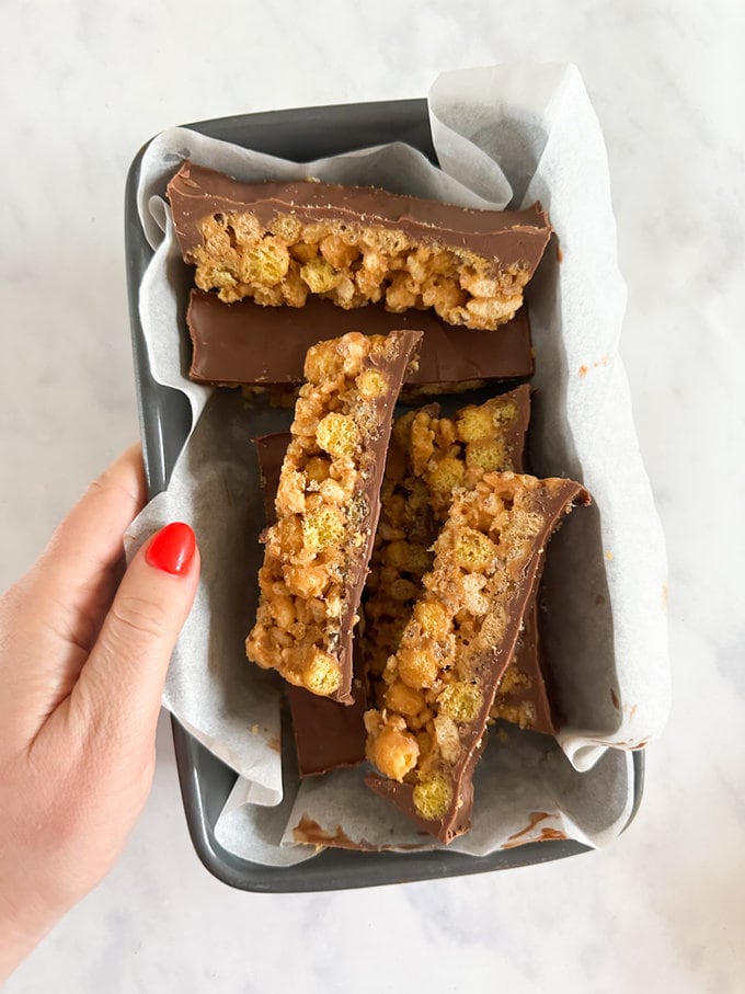 Leftover cereal bars in a presented in a loaf tin lined with grease proof paper.