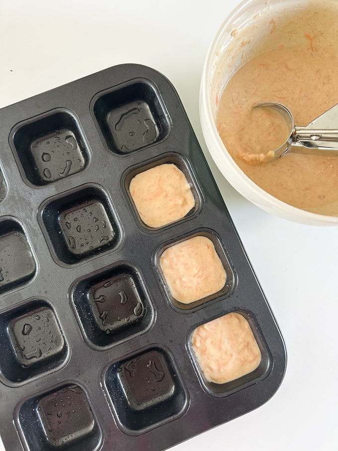 Mini Carrot Banana Bread mixture being added to the muffin tin using a ice cream scoop ready for baking.