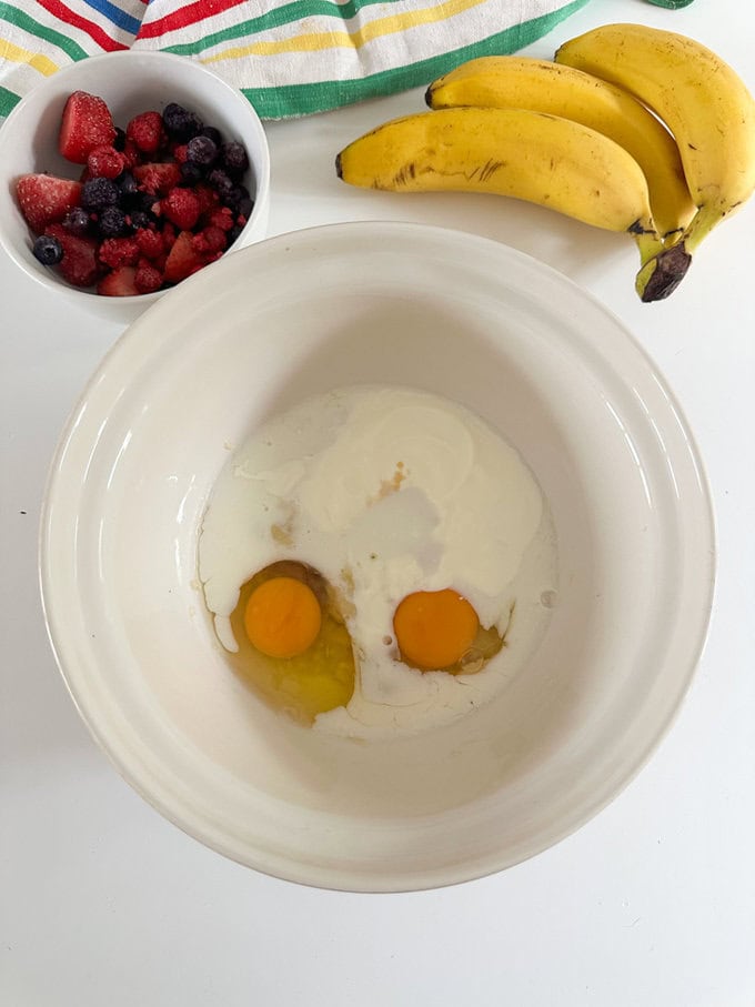 Ingredients for the breakfast cake being added to a large white mixing bowl.