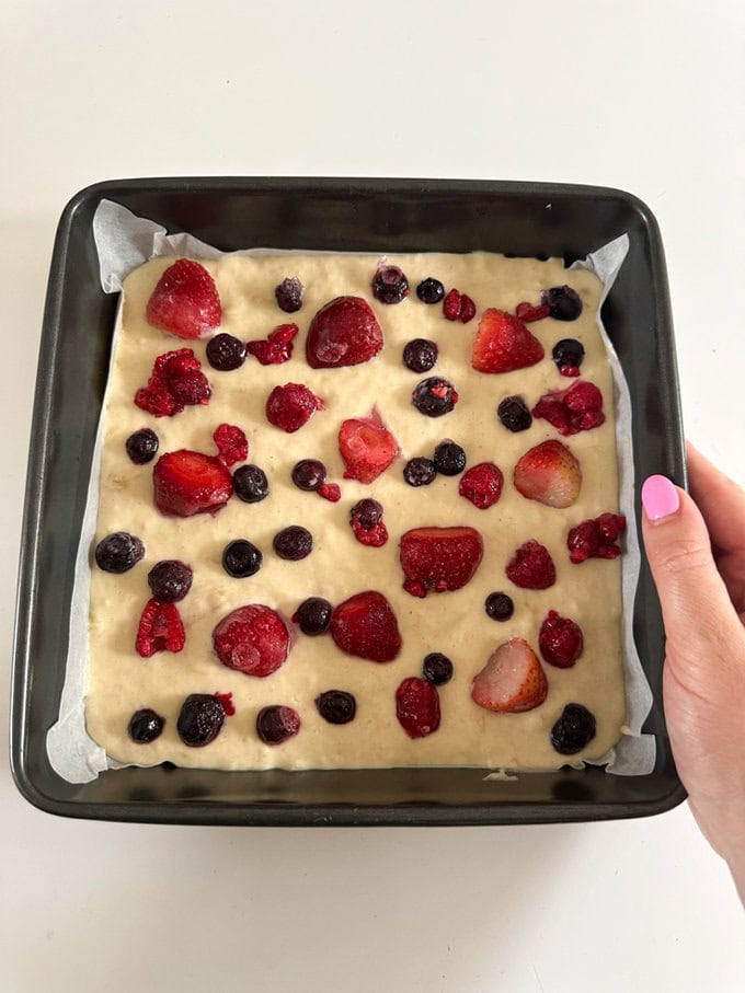 Breakfast cake mixed poured into a oven proof dish and mixed berries added to the top.