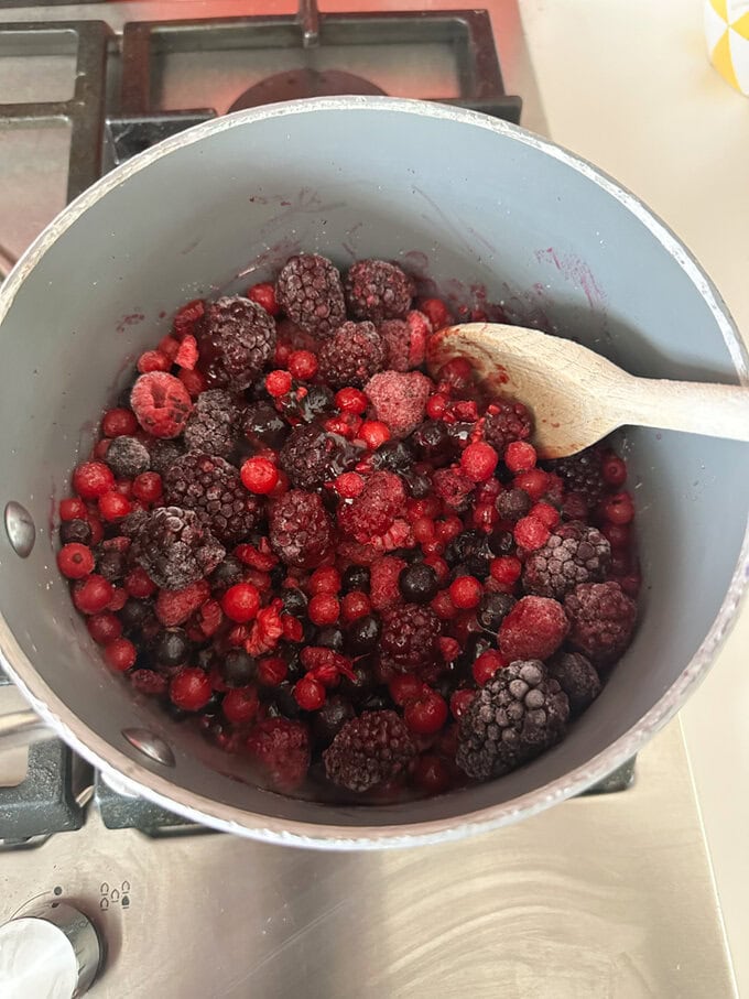 Berries being mixed in a saucepan.