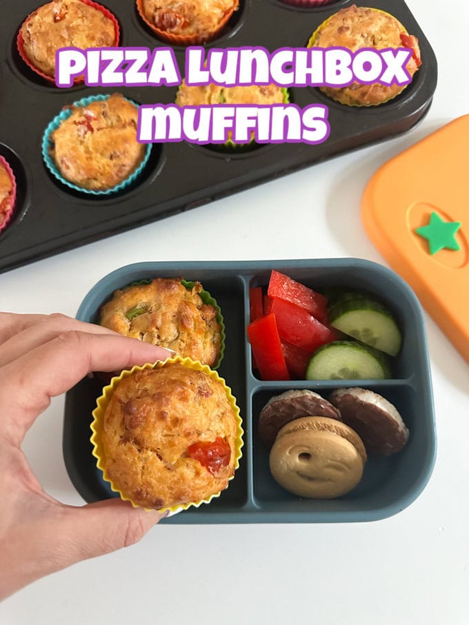 Two Pizza lunchbox muffins presented in a blue silicone divided lunchbox and served with sliced cucumber and red pepper, and some mini chocolate rice cakes and biscuit.