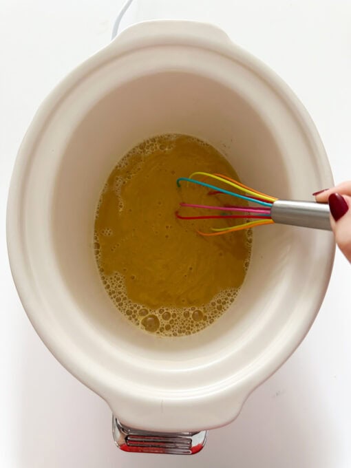 Curry sauce being combined with water in a slow cooker.