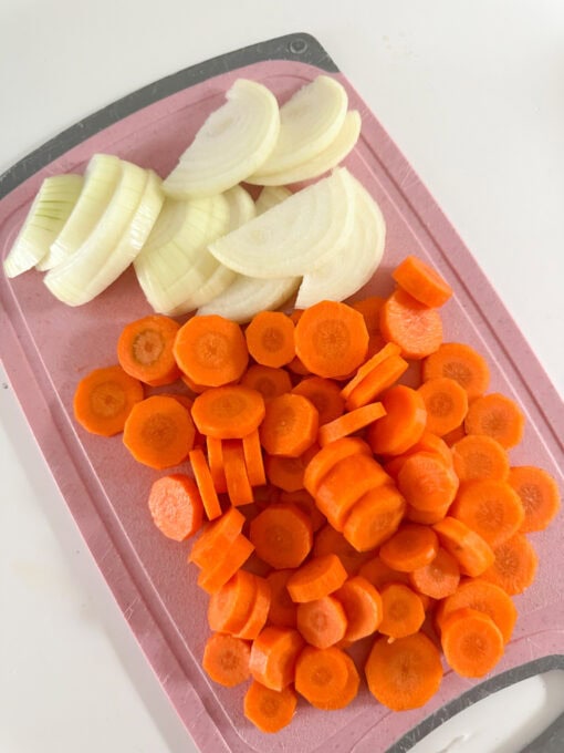 sliced onions and carrots on a chopping board.