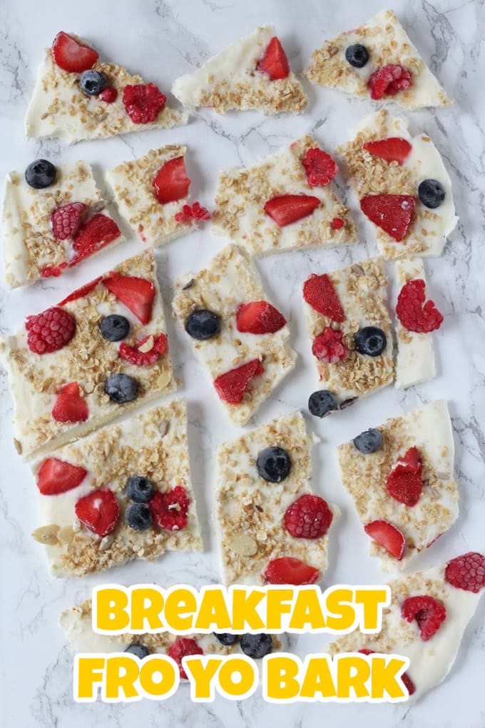 Breakfast Frozen Yogurt Bark cut into irregular shapes and served on a grey and white marble surface.
