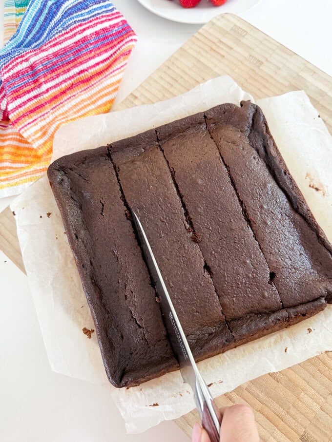 Chocolate cake bars fresh out of the oven and being cut into equal squares.