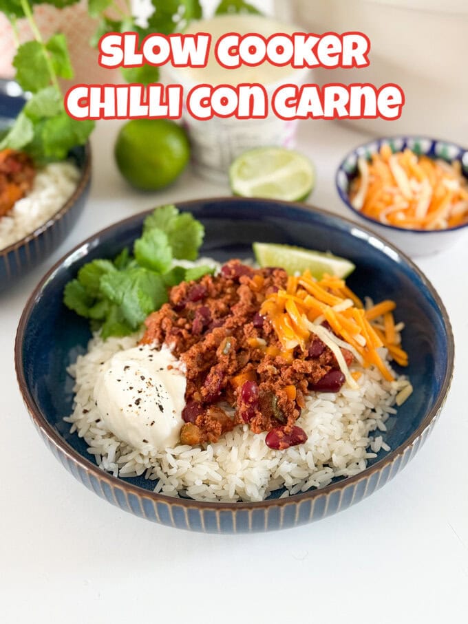 Served with white rice,grated cheese. And garnished with a slice of lime and a sprig of coriander. In a round dark blue bowl.