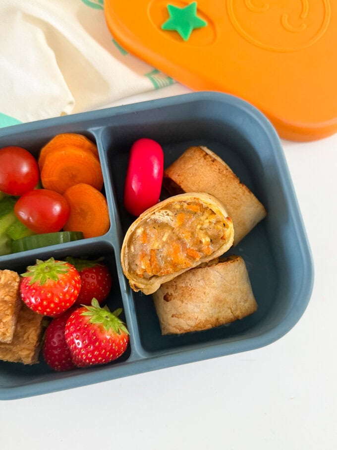 Tasty sausage rolls packed with apple and carrot and made using tortilla wraps. No pastry required! Great for school lunchboxes or lunch at home.

Served in a child's blue lunch box alongside fresh chopped fruit & veggies.