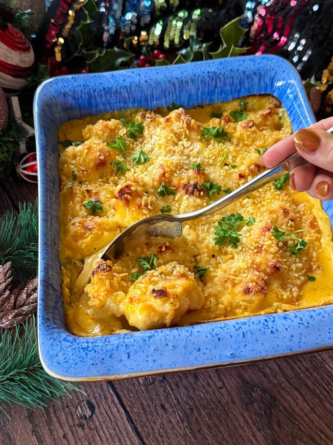A delicious creamy and super cheese Cauliflower Cheese served in a bright blue oven dish.