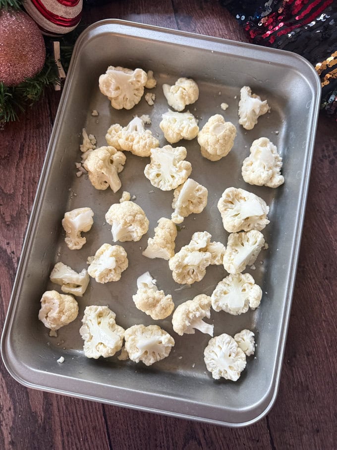 Cauliflower florets in a baking dish ready for the rest of the ingredients to be added on the top.