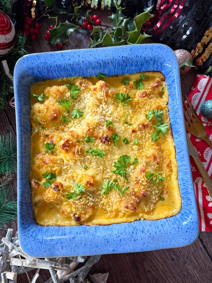 A delicious creamy and super cheese Cauliflower Cheese served in a bright blue oven dish.