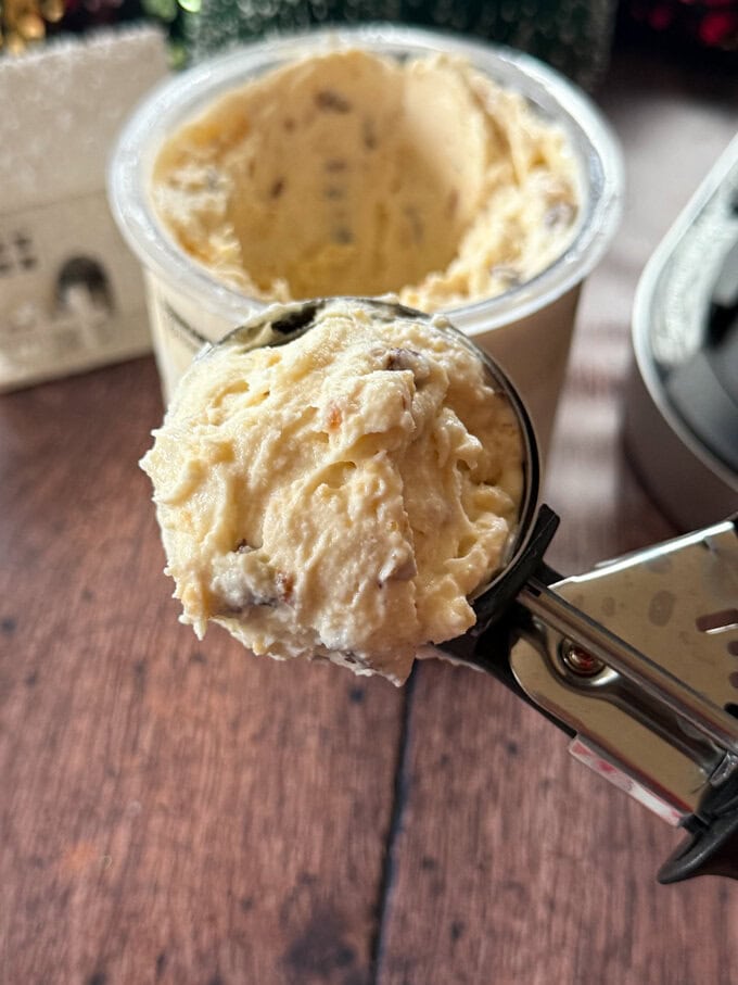 A large scoop of mince pic ice cream on a stainless steel ice cream scoop.