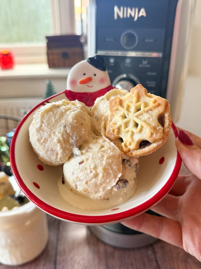 A festive snowman bowl with two large scoops of mince pie ice cream, with a mince on the side.