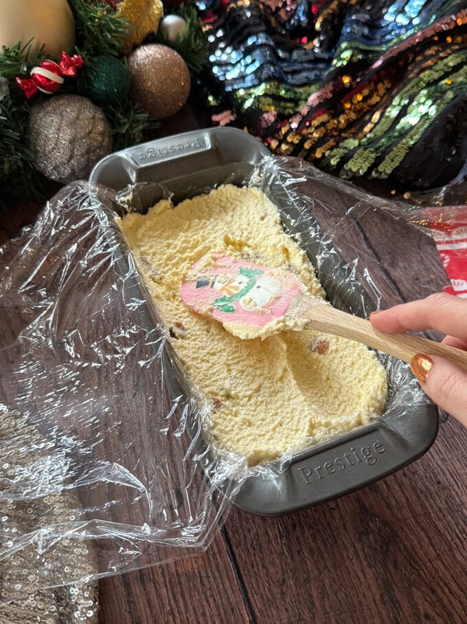 Ingredients going into lined baking tin using a snowman spatula. 