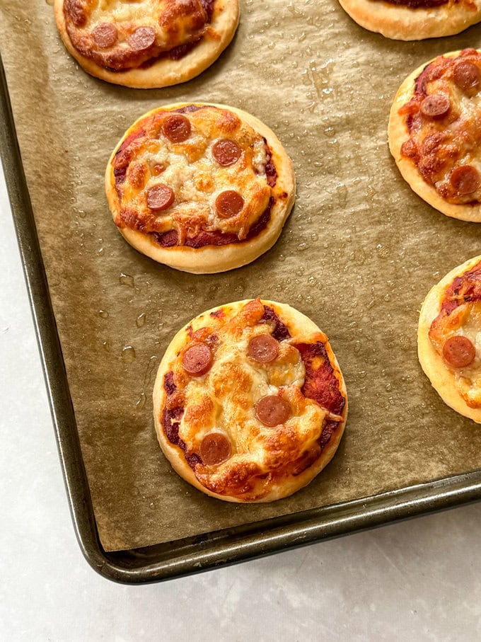 Mini pizzas arranged on a baking tray, fresh out of the oven.