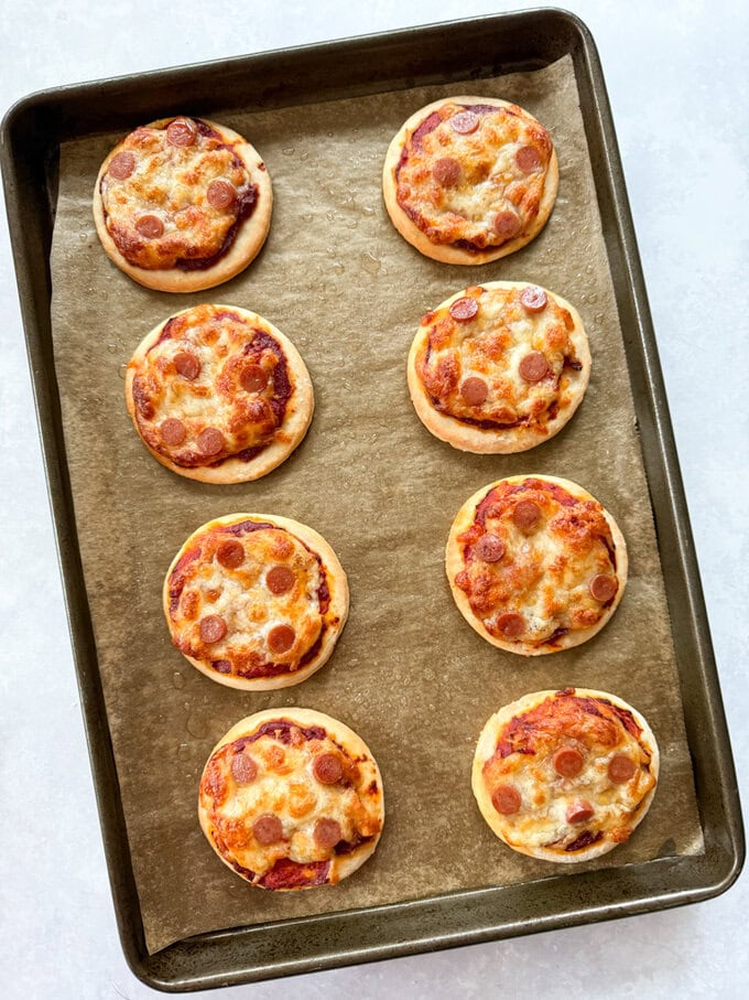 Mini pizzas arranged on a baking tray, fresh out of the oven.