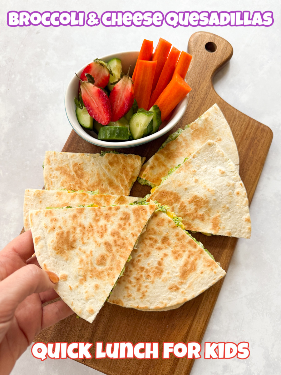 Broccoli quesadillas arranged on a wooden chopping board, with a small bowl of fresh chopped fruit & veggies.