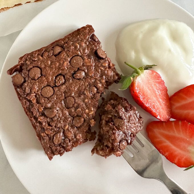 Chocolate Oat Brownie served on a white plate with yogurt and fresh berries.