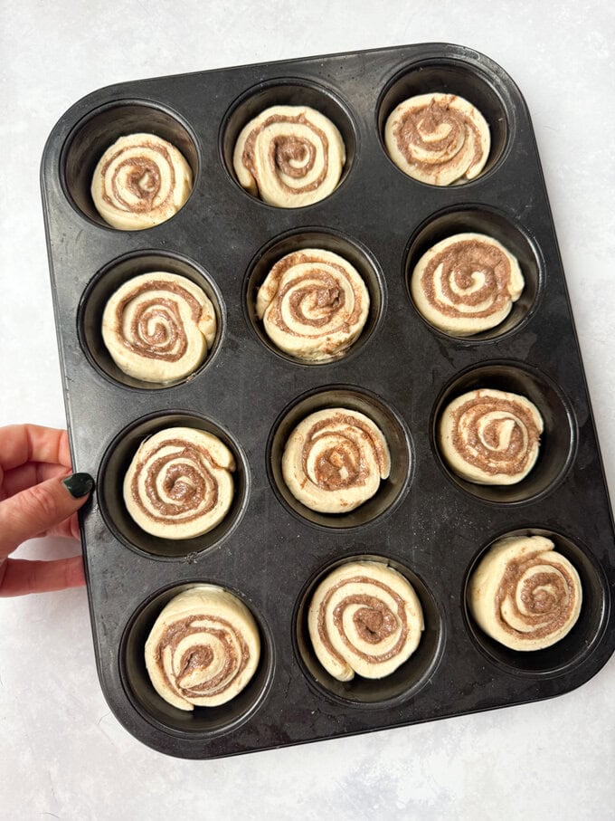 Disposez les brioches à la cannelle dans un moule à muffins, prêts à aller au four.