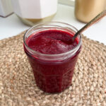 Pot de confiture transparent rempli de confiture de chia avec une cuillère à soupe pour servir.