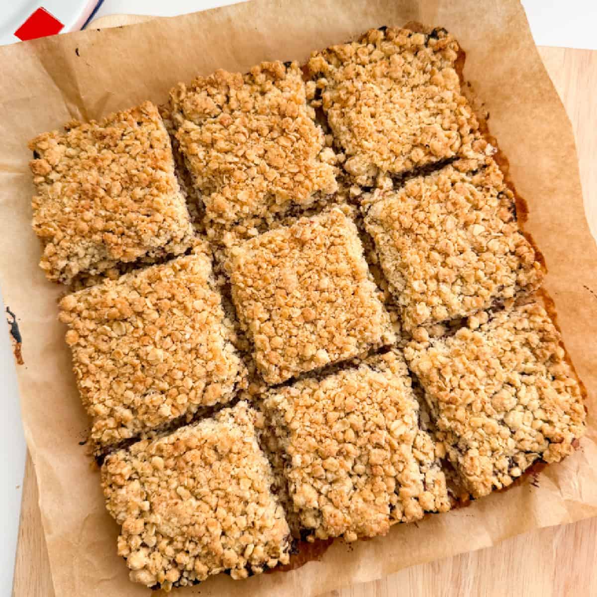 Jam Crumble bars on grease proof paper sectioned in to edible squares, ready for eating.
