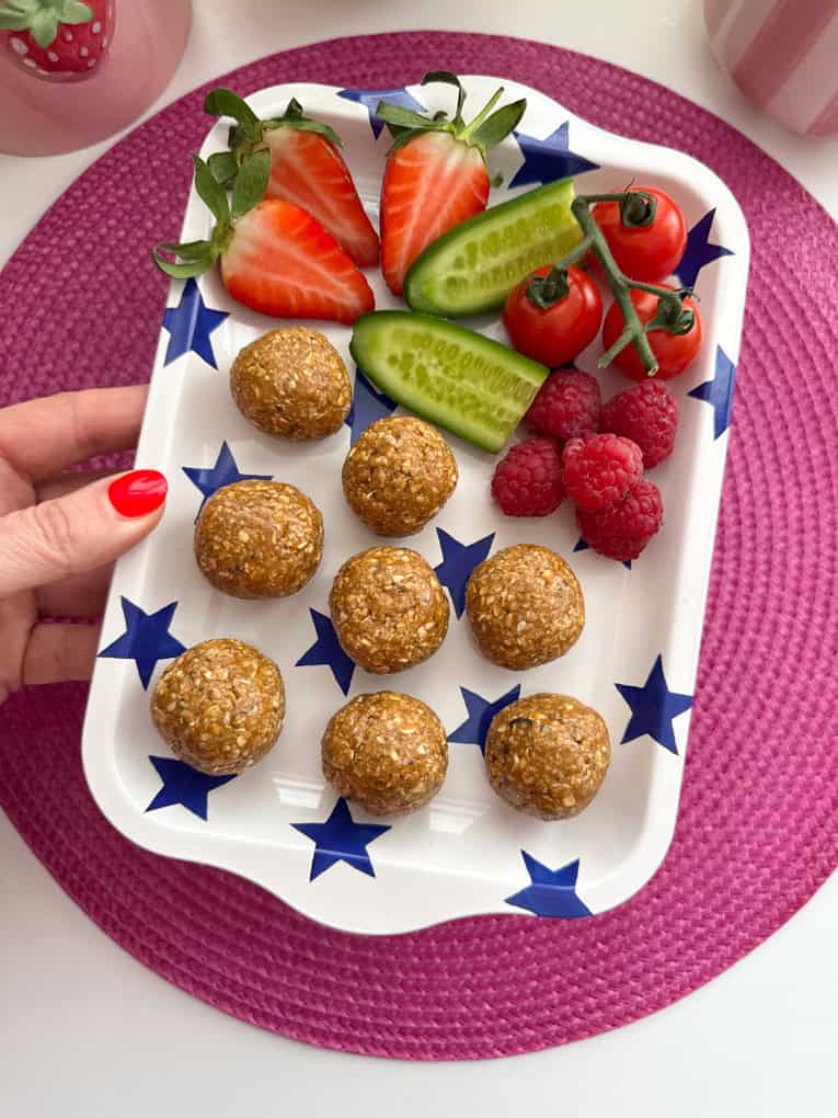 Biscoff-Haferflockenriegel, serviert auf einem weiß-blauen, sternförmigen Tablett, mit frisch gehackten Beeren und Gurke.