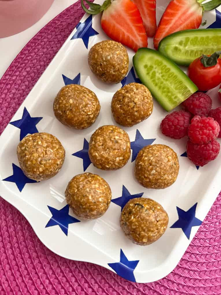 Biscoff-Haferflockenriegel, serviert auf einem weiß-blauen, sternförmigen Tablett, mit frisch gehackten Beeren und Gurke.