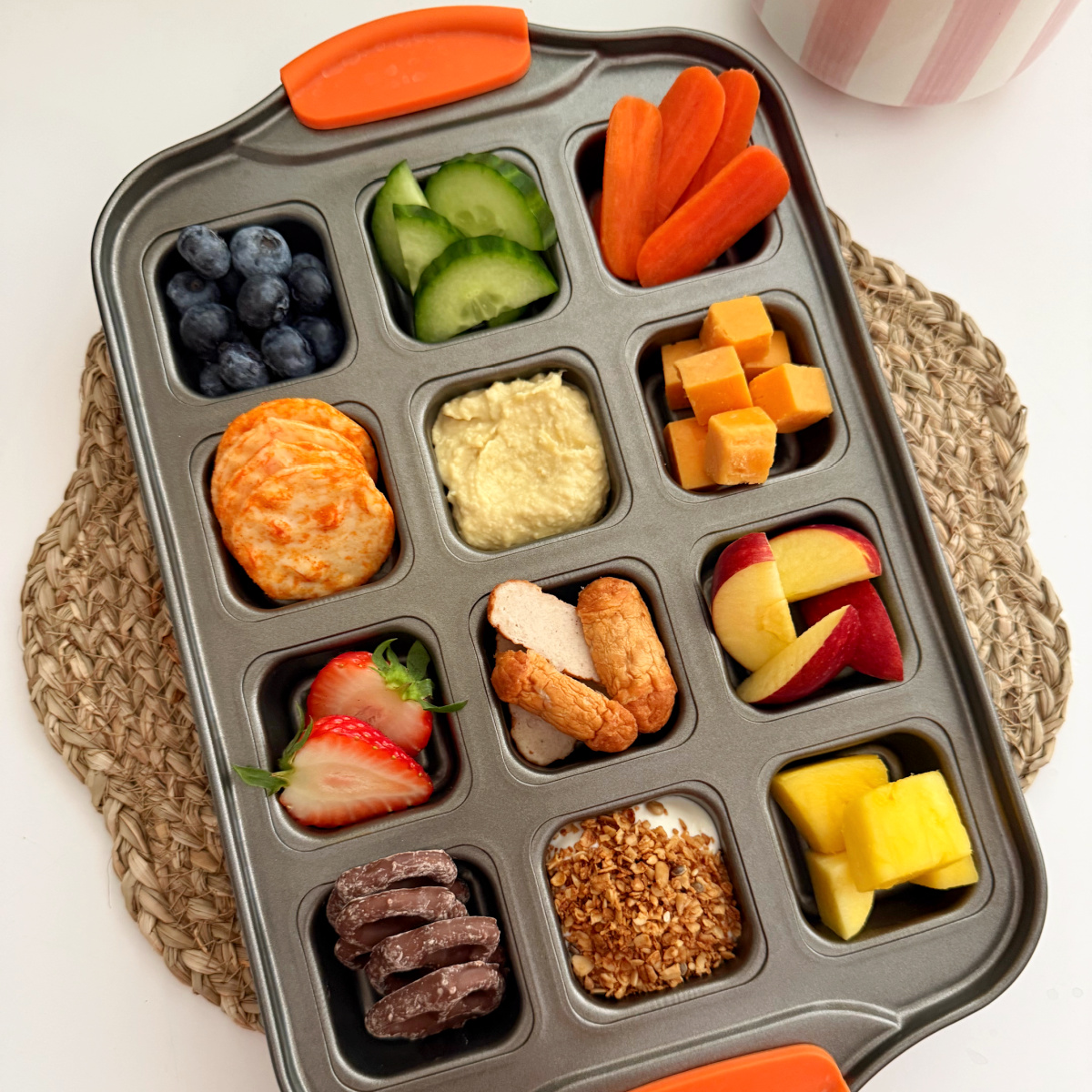 Different snacks arranged in a square muffin baking tray.