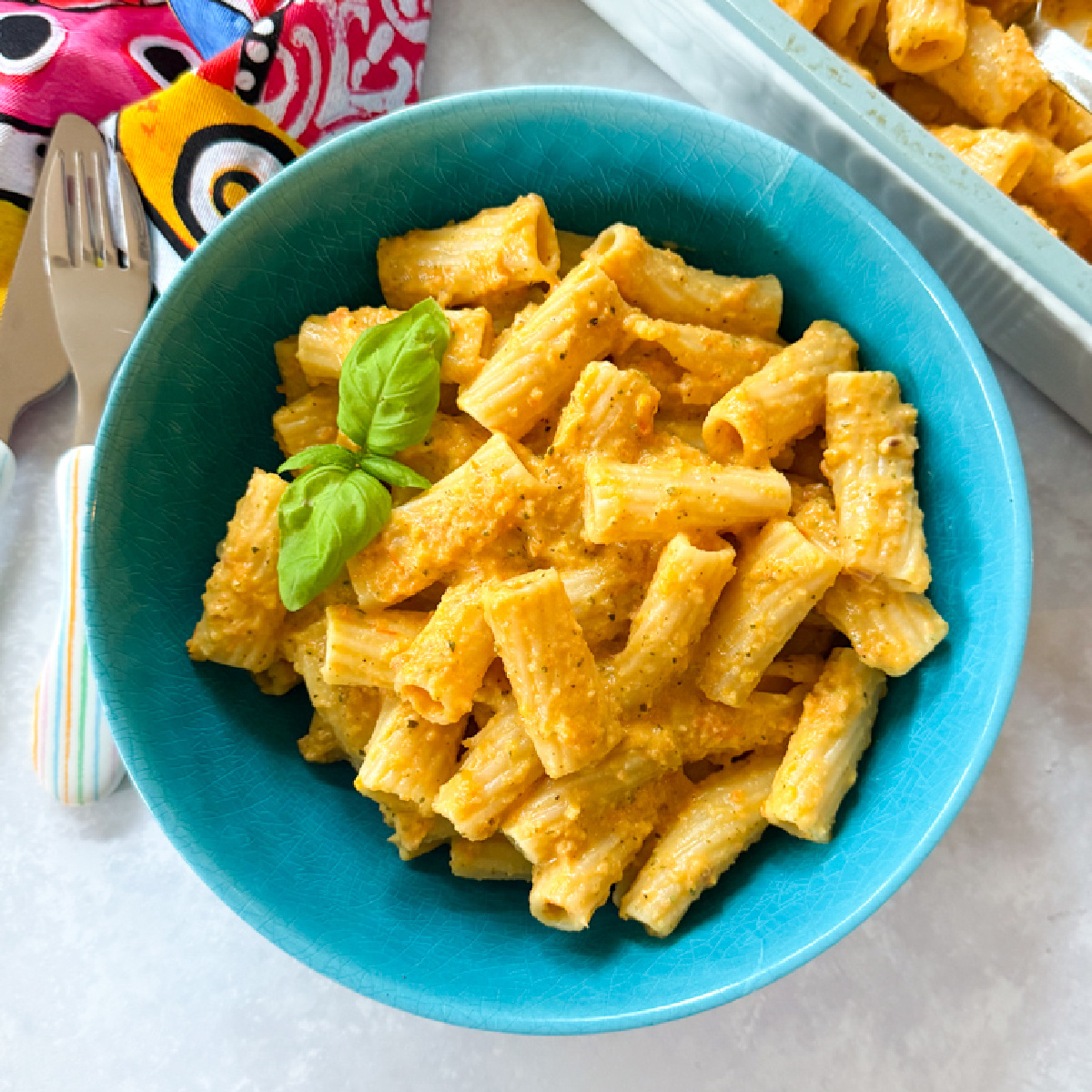 Roasted Veg & boursin pasta served in a baby blue pasta bowl with a sprig of basil.